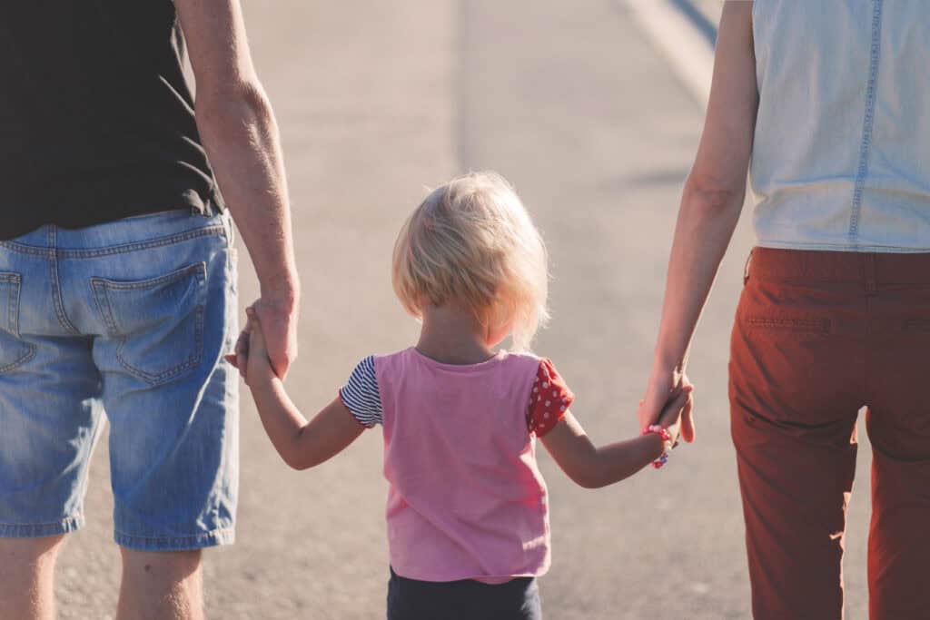 mom and dad holding little girl's hand