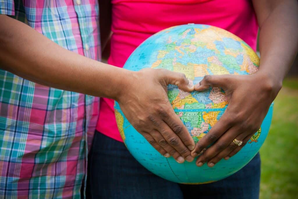 couple holding blow up world ball, hands in heart around counrty