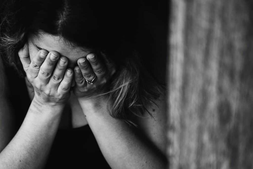 married woman holding head in hands; sad