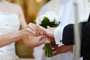 Bride putting a ring on groom's finger during wedding ceremony